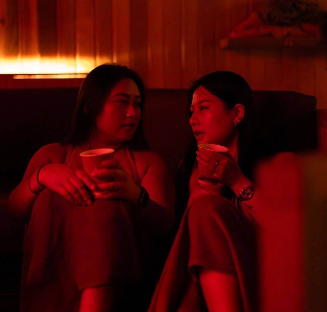 Two friends talking in a red-lit lounge